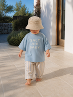 Toddler walking outdoors wearing Boo and Coo Salt Air Baby oversized t-shirt